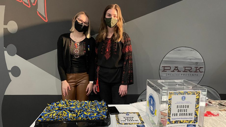 Adrianna Krawczuk and Marysa Fosty standing in front of a table of blue and yellow ribbons.