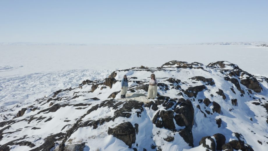 Two people standing on snow capped rocks in the Republic of Tartupaluk.