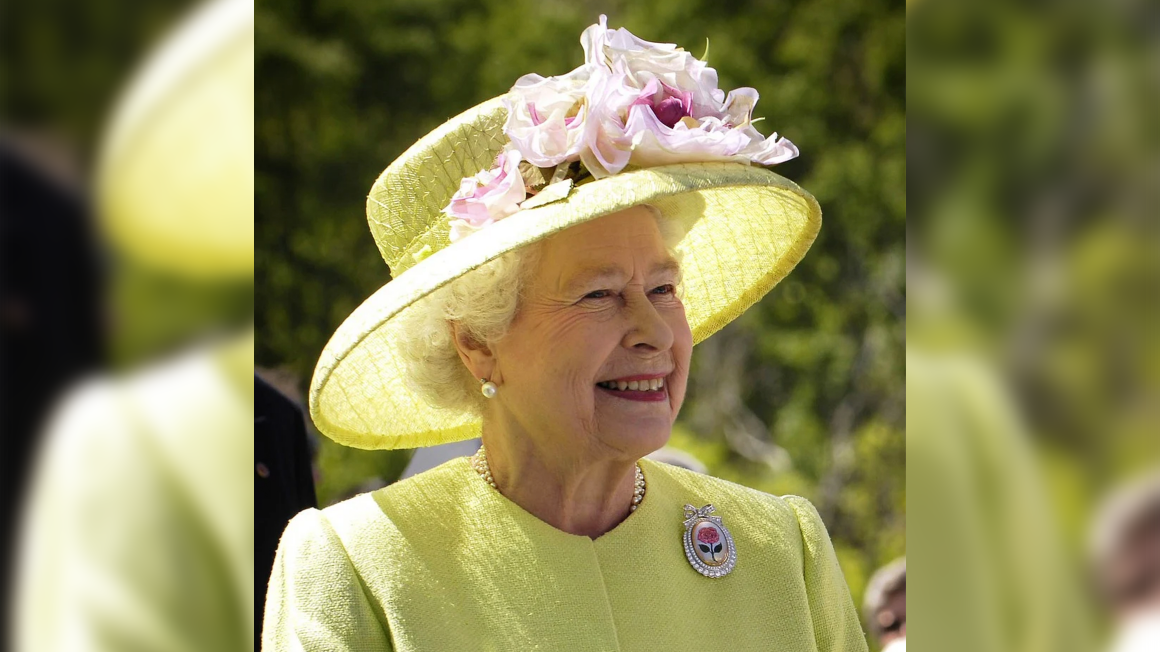 Queen Elizabeth wearing all yellow and hat with a pink flower.