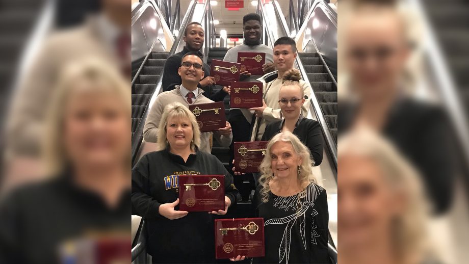 Members of University of Winnipeg Golden Key show off their seven awards standing on stairs.