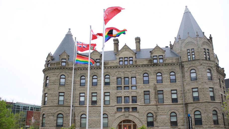 The Progress and Two-Spirit flags flying in front of Wesley Hall.