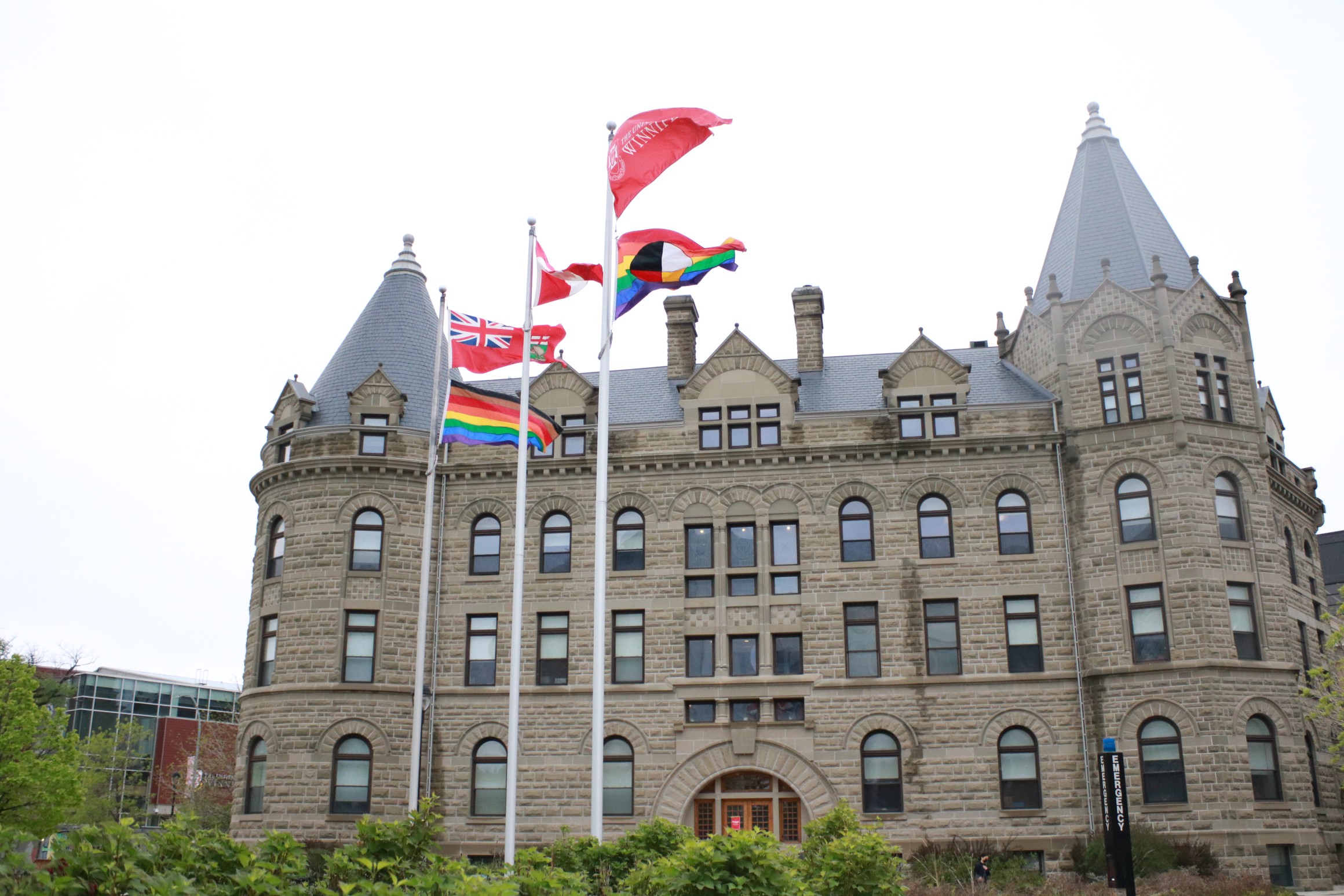 The Progress and Two-Spirit flags flying in front of Wesley Hall.