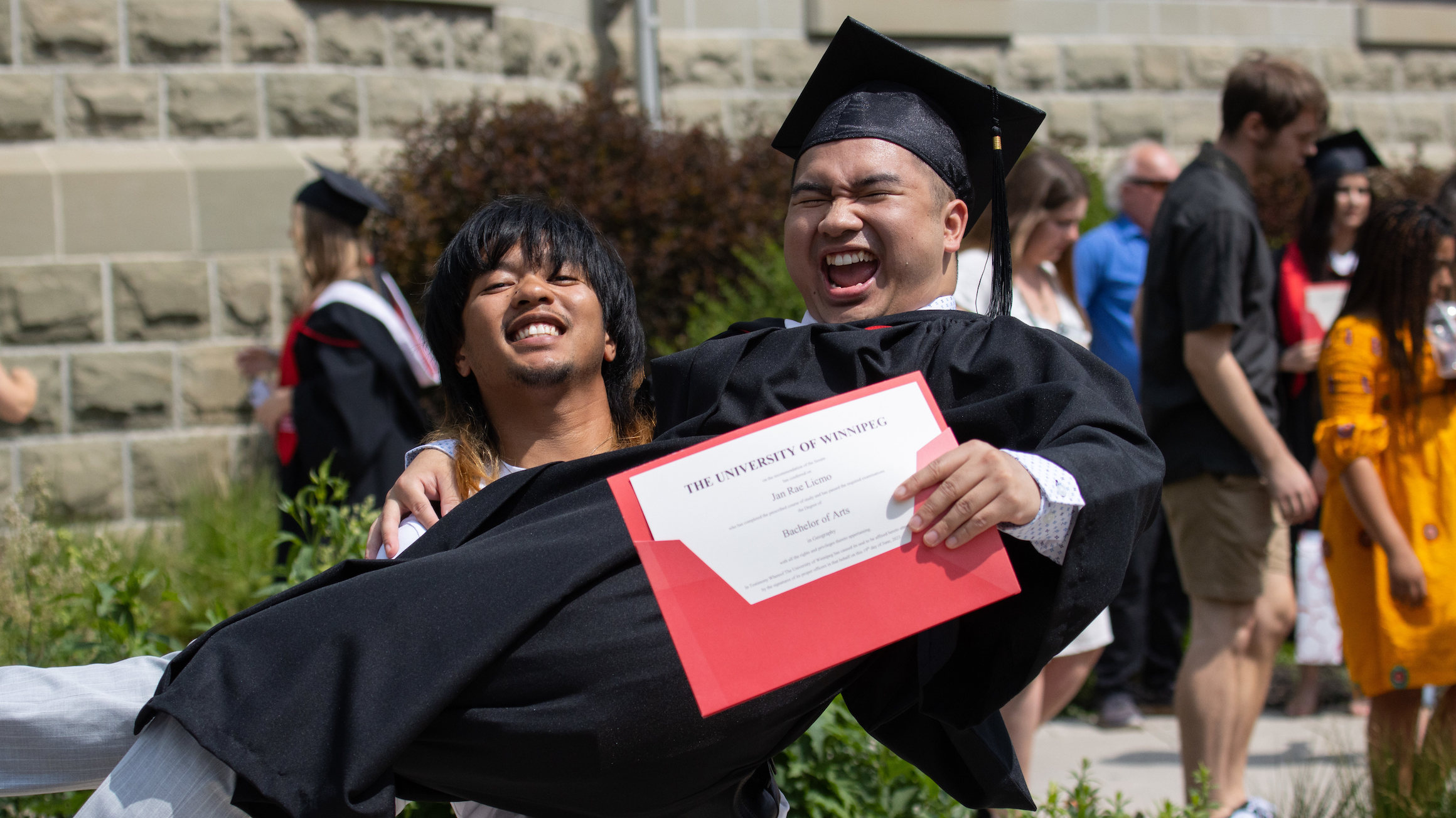 A UWinnipeg graduate celebrates with a friend.