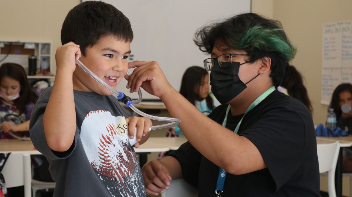 A student listens to his heartbeat with a stethoscope.