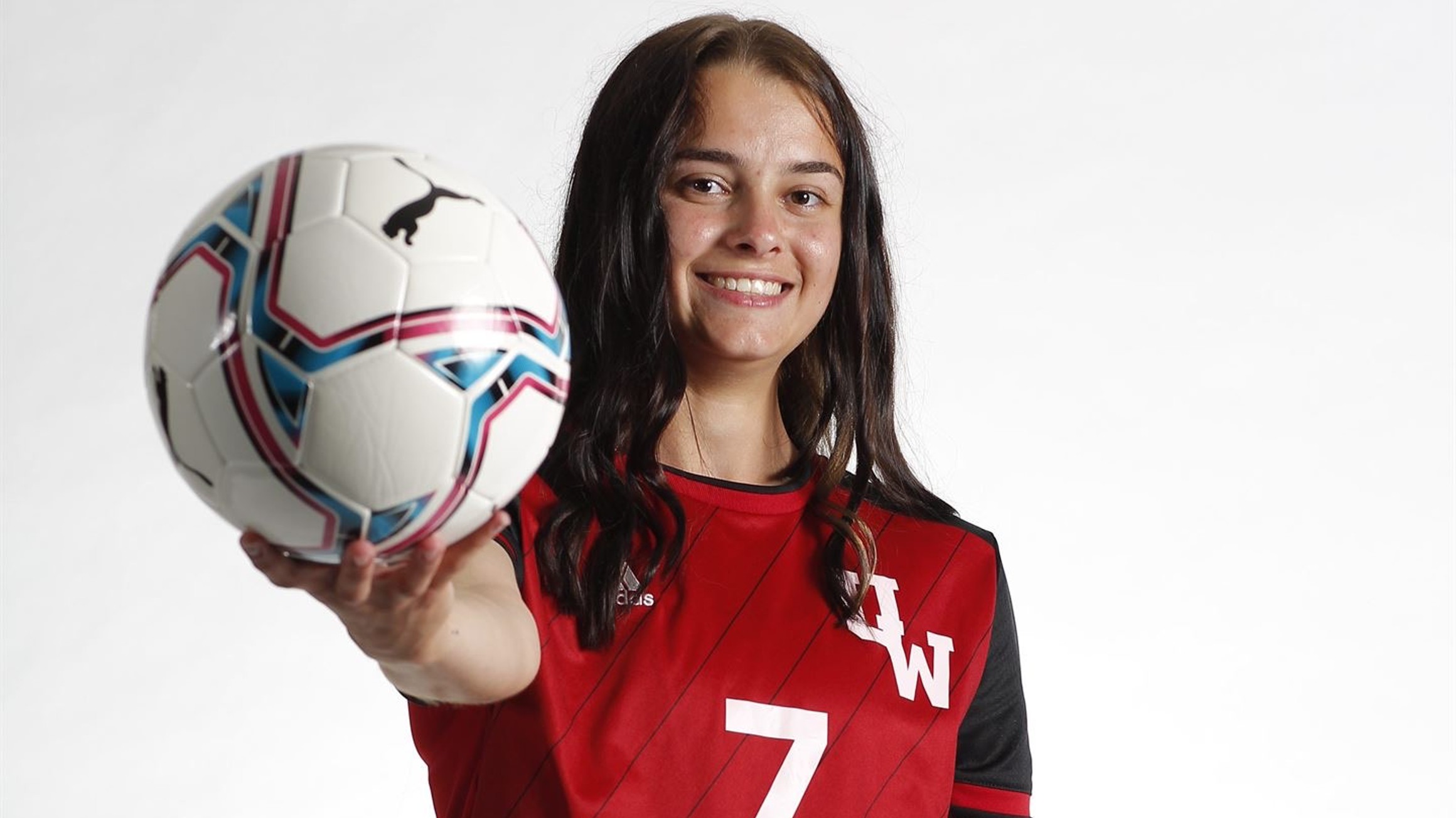 UWinnipeg student-athlete Emma Friesen holding a soccer ball while wearing a Wesmen Athletics jersey.