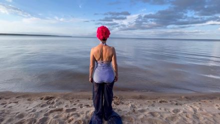Woman in bathing suit faces away toward Lake Winnipeg.