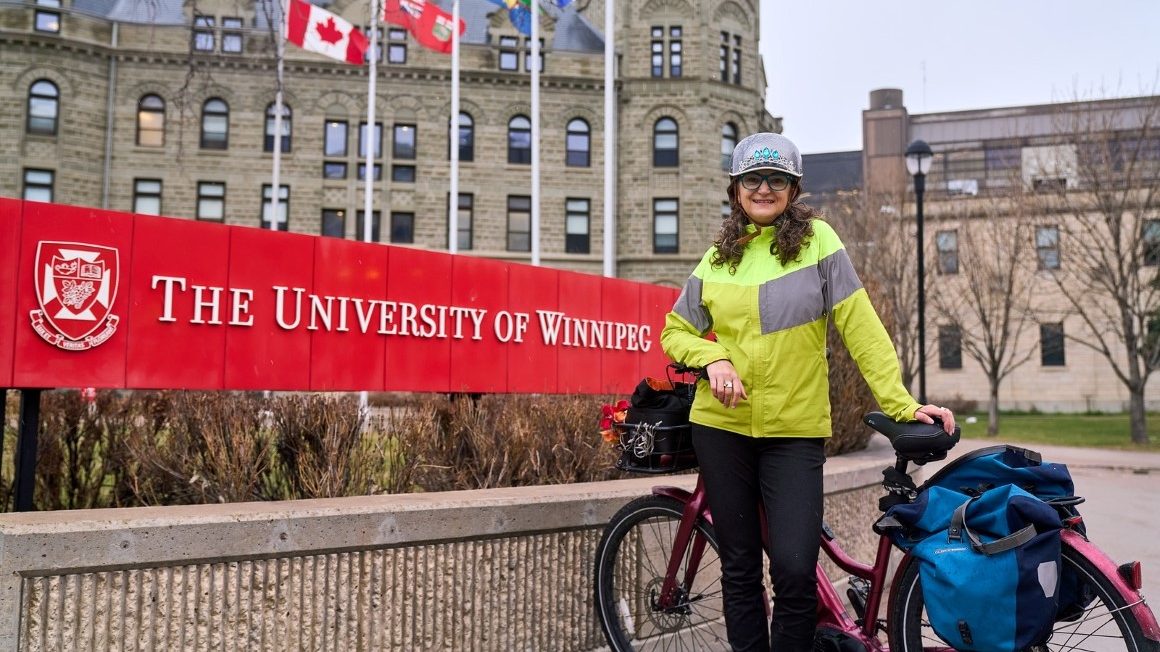 Patty Wiens stands in front of Wesley Hall with her e-bike.
