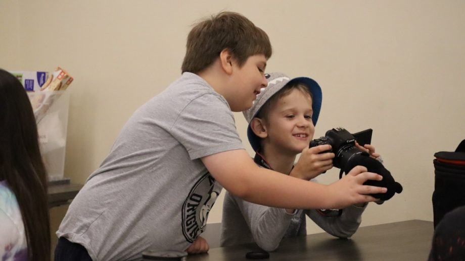 Two children learn how to use a digital camera.