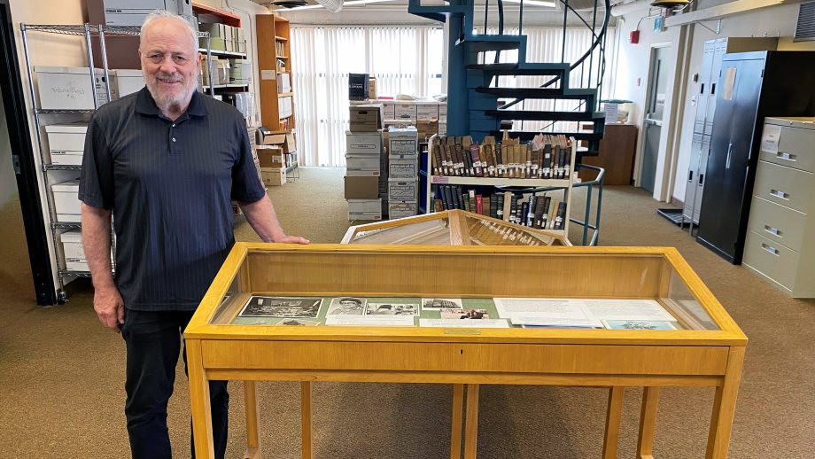 Steven Schipper standing in front of old books and a winding metal blue staircase.