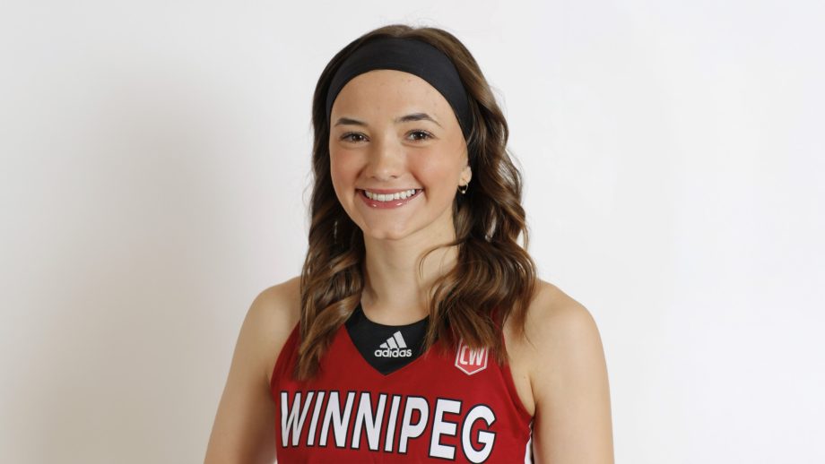 Female student smiles while wearing a red Wesmen basketball jersey and a black headband, standing against a white backdrop.