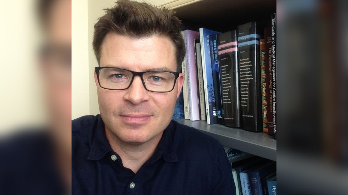 Craig Willis in front of a bookshelf.