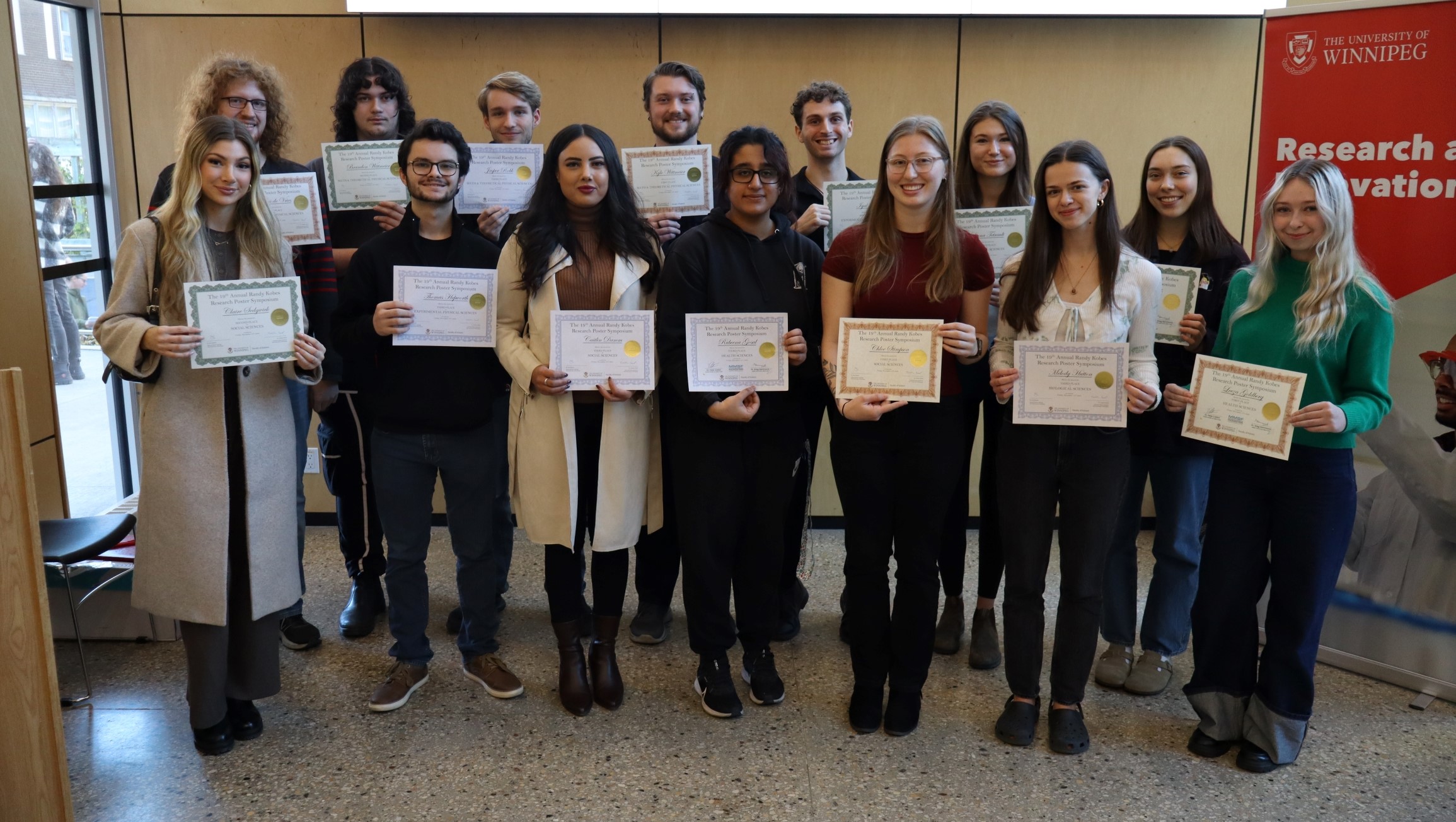 Students stand in two rows holding certificates.