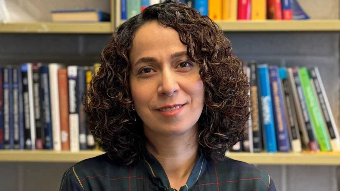 Dr. Zeinab Mashreghi standing in front of a book case.