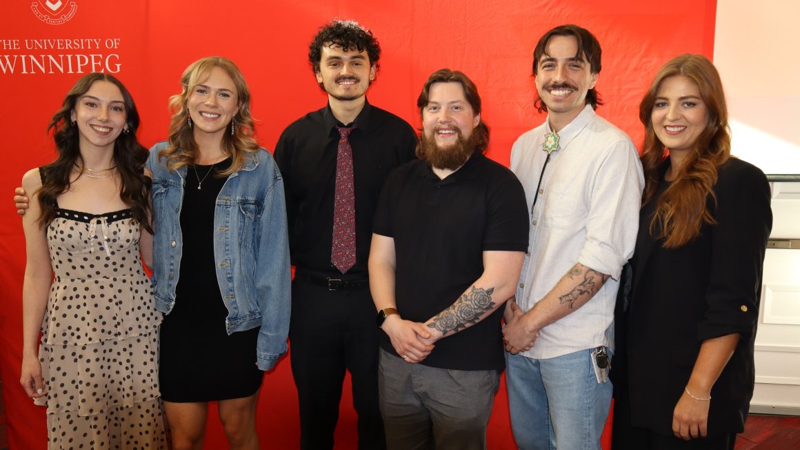 Six students stand in front of a red backdrop.