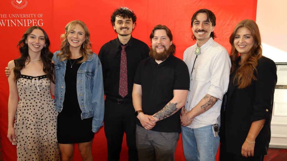 Six students stand in front of a red backdrop.