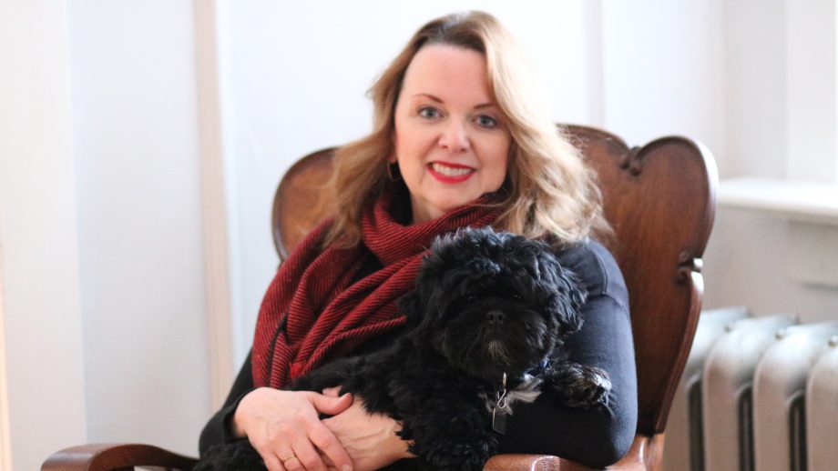 Dr. Jane Barter holding her black dog on her lap