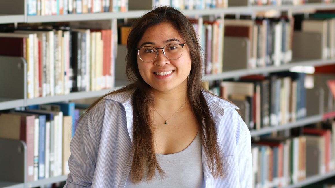 Nicole Valencia standing in the library stacks