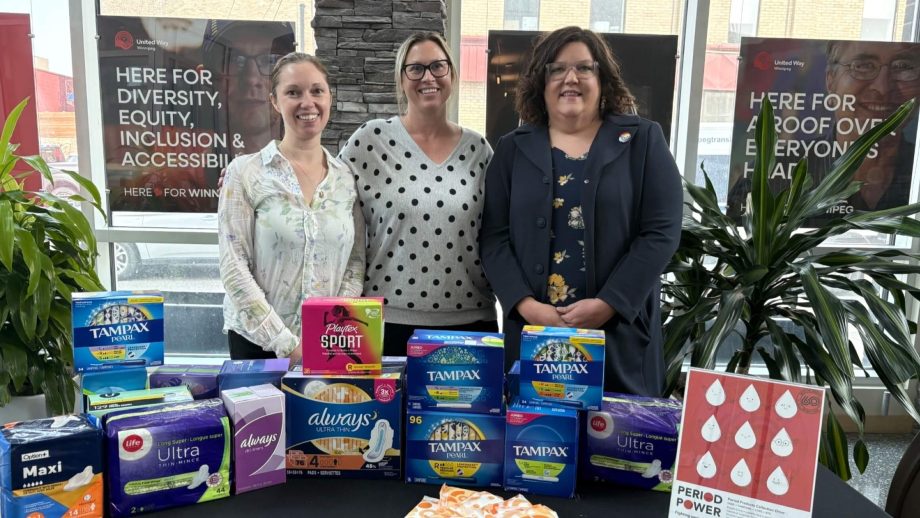 people stand behind table covered in menstrual supplies