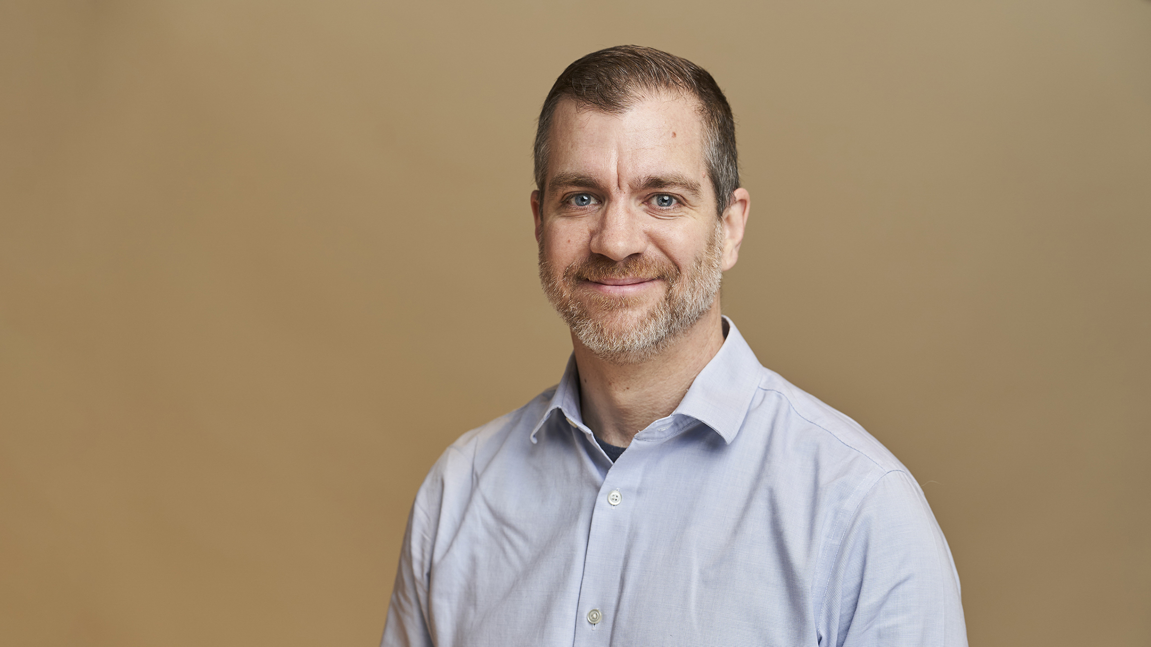 Dr. Brandon Christopher in front of a tan background.