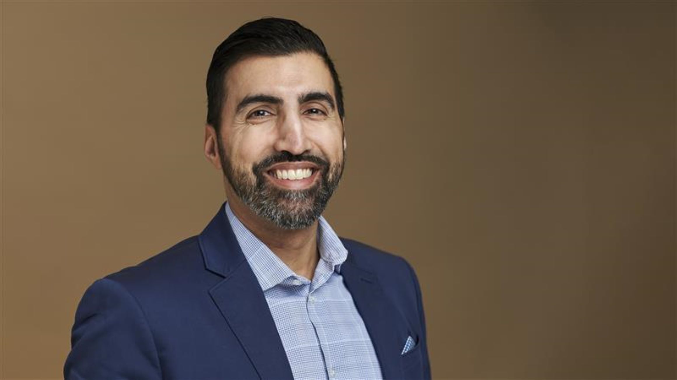 Osaed Khan in front of a tan background.