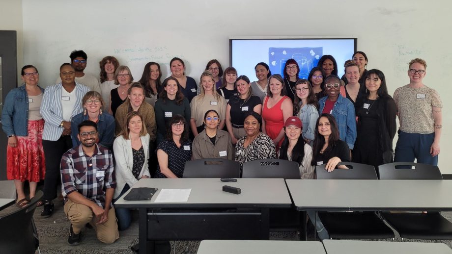 Participants of the Community-Based Research Summer Institute in a classroom in three rows; some seated, some standing.