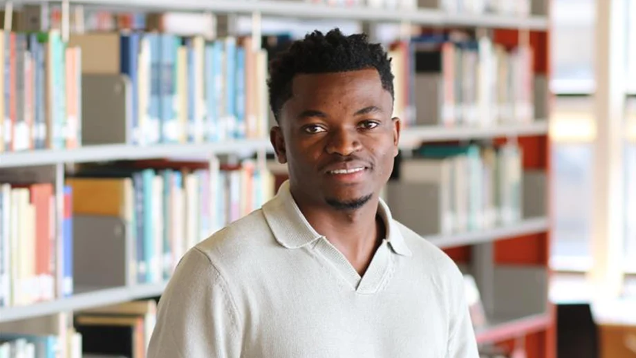 Modeste Katotoka standing in a library.