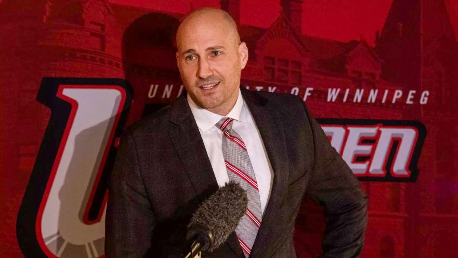 Mike Raimbault in front of the Wesmen logo.