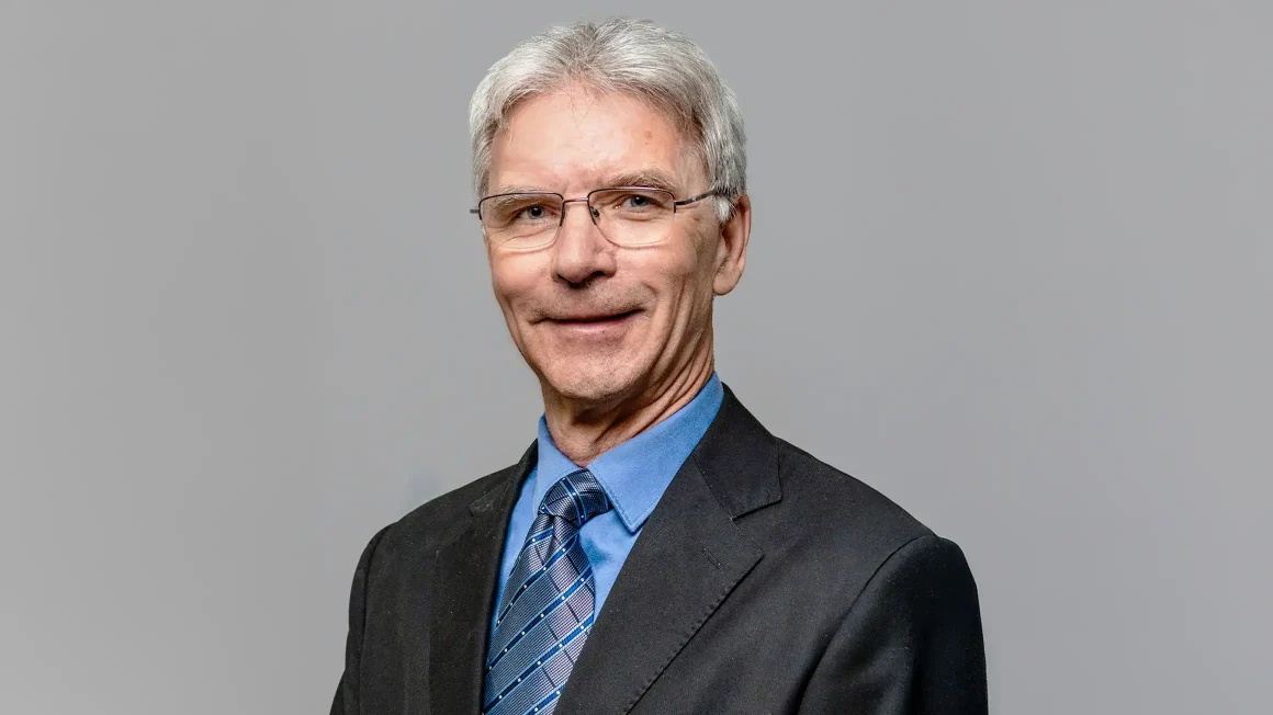 Dr. Glen Bergeron standing in front of a grey background.