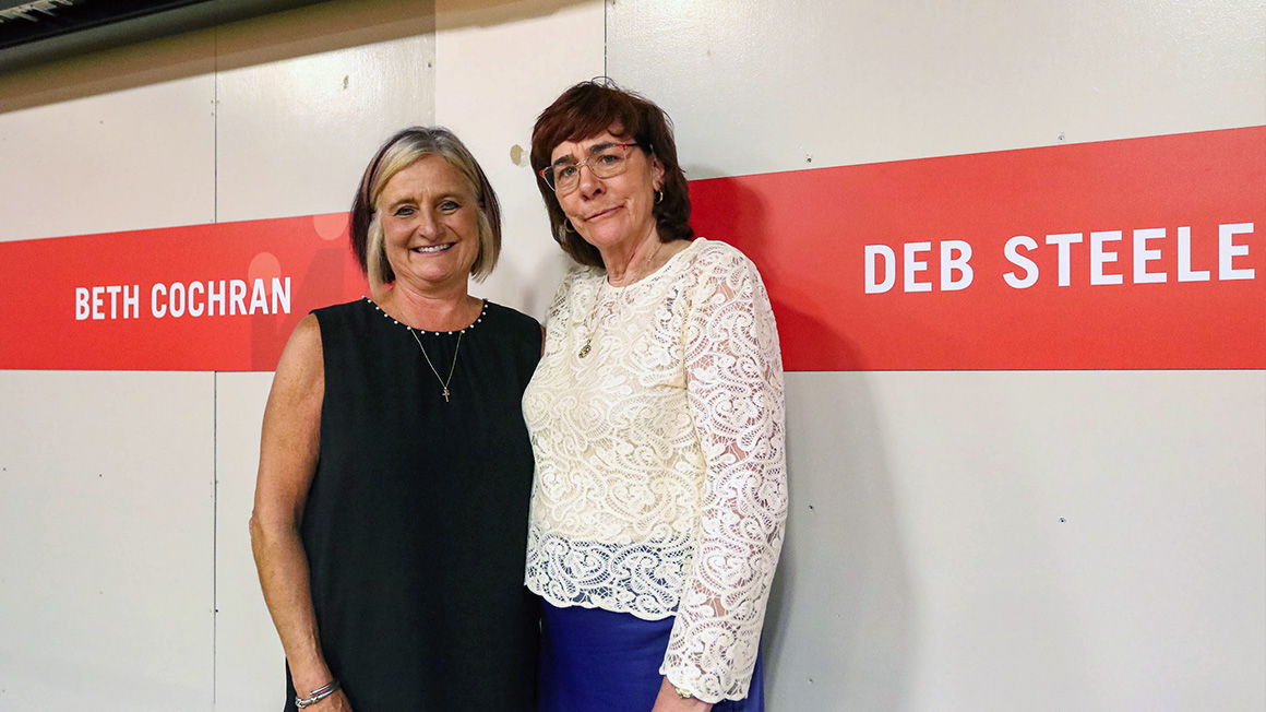 Beth and Deb standing beside nameplates.