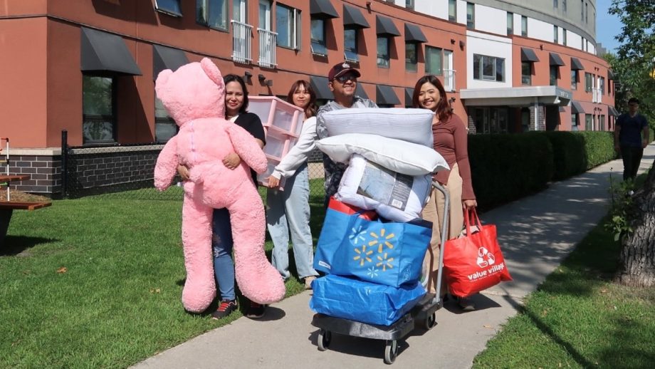 People hauling belongings into a dorm building.