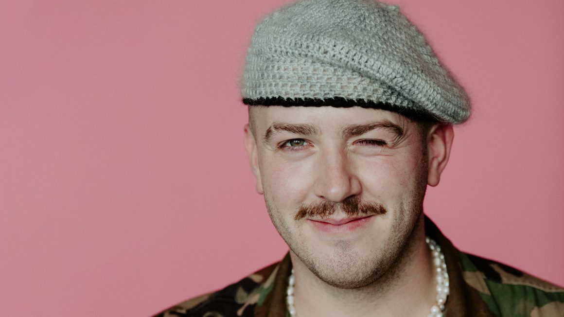 headshot of Lucas Morneau with a pink background.