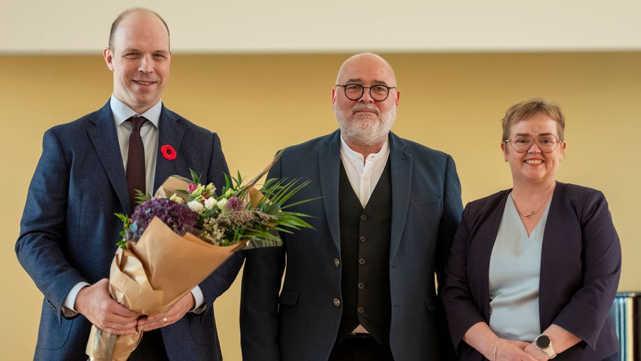 Dr. Ryan Eyford holding a bouquet of flowers standing next to Logi Einarsson, Iceland’s Minister of Culture, Innovation, and Higher Education and Silja Bára R. Ómarsdóttir, Rector (i.e., President) of the University of Iceland.