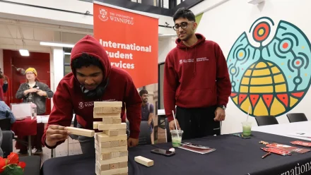 Two people playing a game on a table in front of a banner.