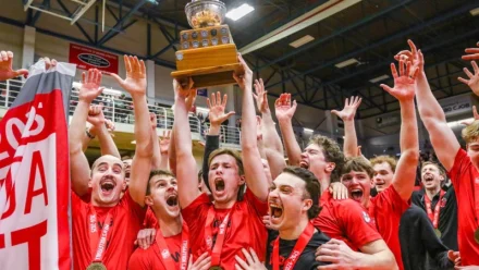 Volleyball team holding up trophy.