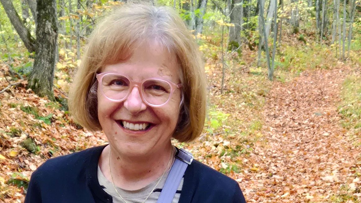 Sandy is standing on a path in forest.
