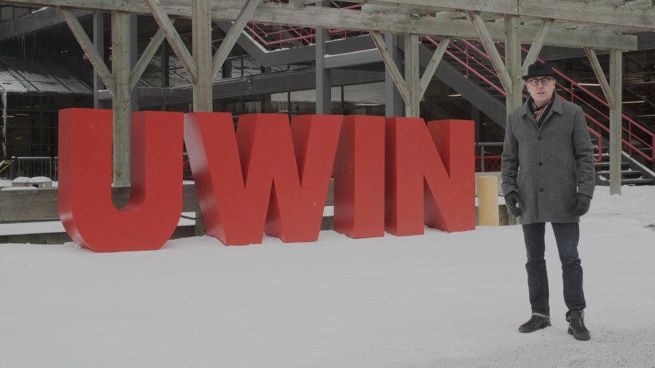 UWinnipeg interim president Jino Distasio standing in the snow in front of red UWIN sign