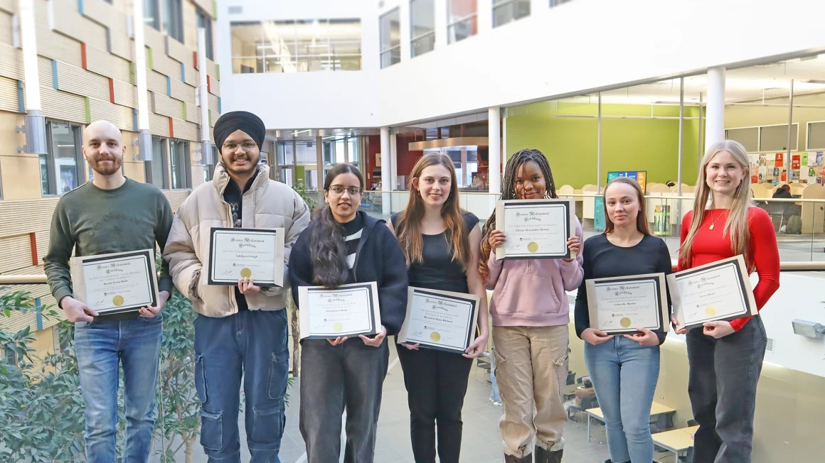 Chemistry award recipients Kurtis Boily, Sahilpreet Singh, Simarpreet Kaur, Kiersten Hiebert, Chiara Martin, Gabrielle Martin, Leiva Mann stand with their awards in an atrium.
