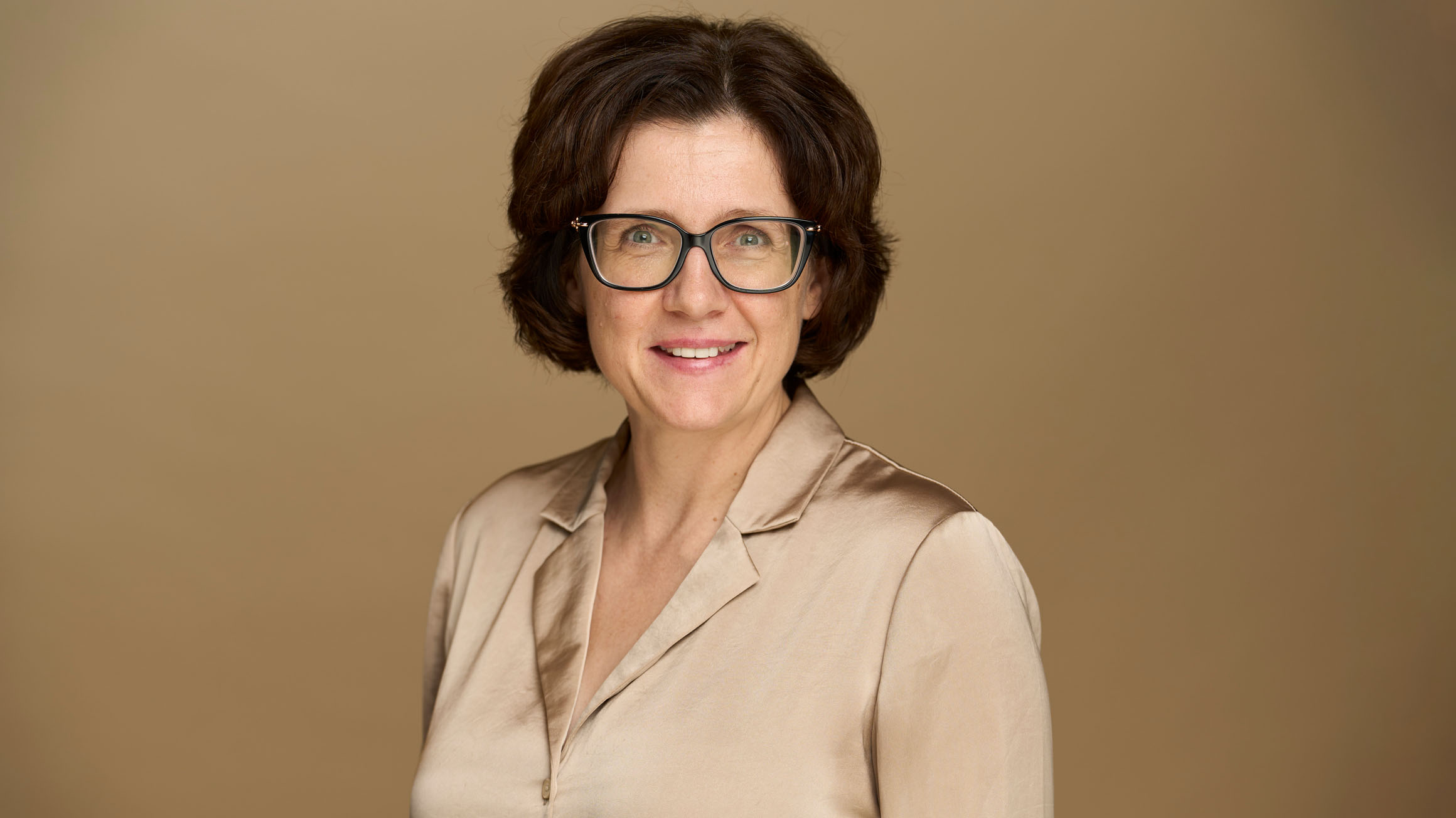 A headshot of Dr. Anna Stokke with a beige background