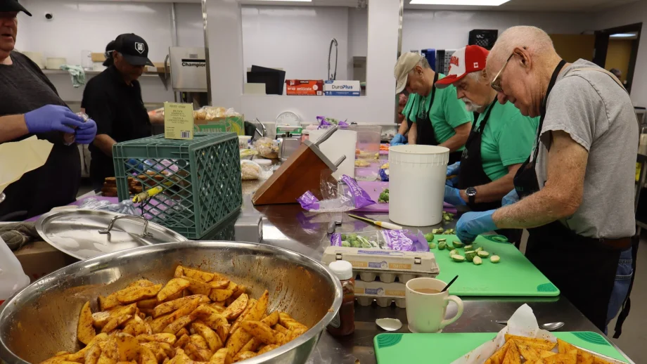Volunteers work at a table chopping vegetables.