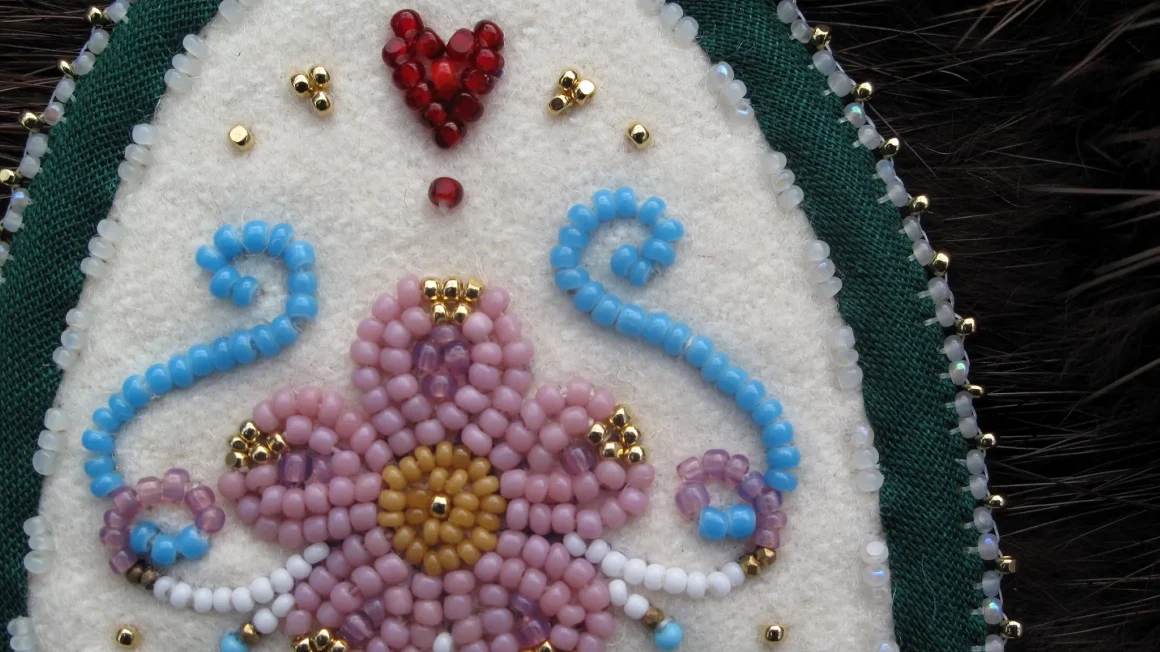 Detail of beaded earrings featuring a pink beaded flower.