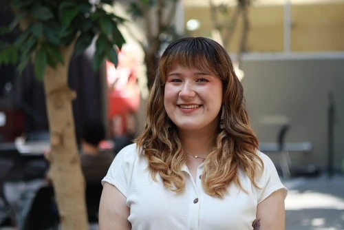 A student smiles in an indoor atrium.