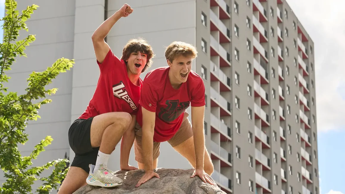 Two male students in red shirts pose on top of The Rock.