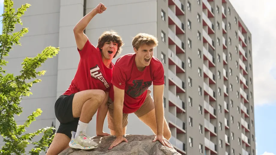 Two male students in red shirts pose on top of The Rock.