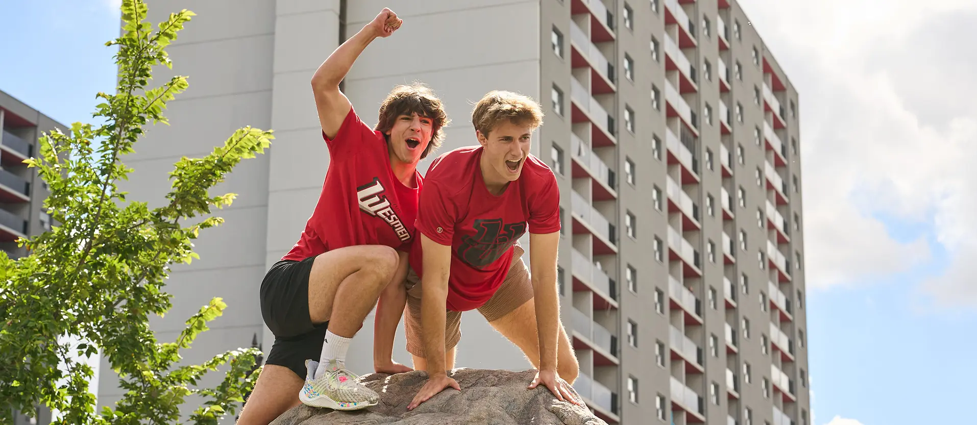 Two male students in red shirts pose on top of The Rock.