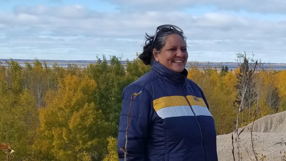 Sr. Wilson standing outside in a blue jacket with trees in the background.