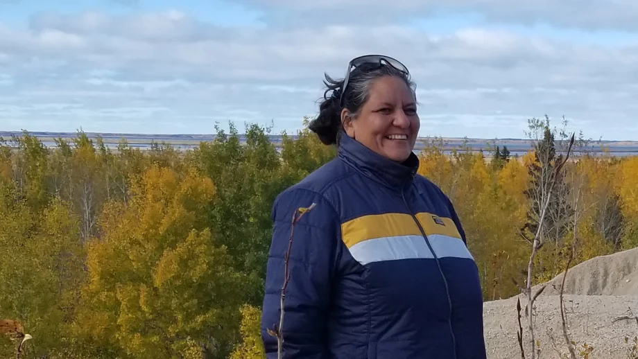 Sr. Wilson standing outside in a blue jacket with trees in the background.