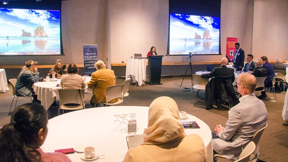 People in a conference room with large screens on either side of the room.