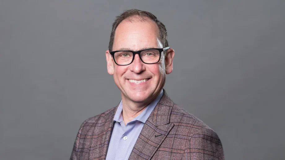 Dr. Eddy Lang in a suit in front of a grey background.