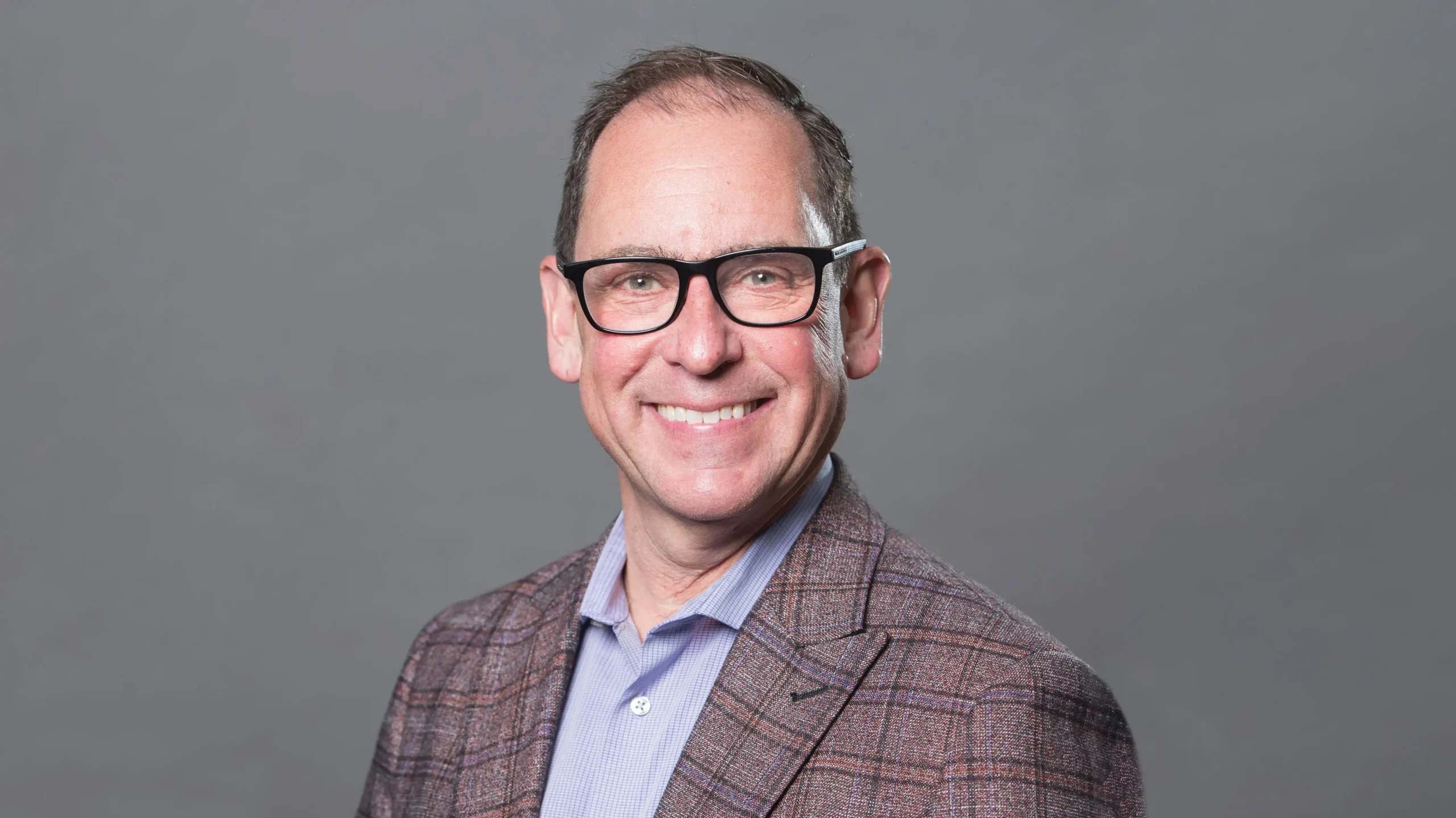Dr. Eddy Lang in a suit in front of a grey background.
